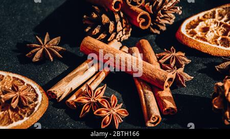 Hintergrund trockener Orangen-, Zimt- und Sternanis, Zutaten zur Zubereitung Glühwein auf schwarzem Grund Stockfoto