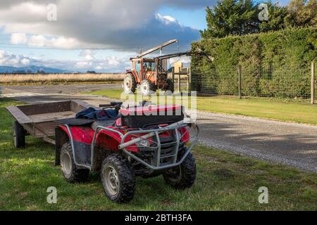 Annat, Canterbury, Neuseeland, Mai 26 2020: Eine Heckenschere bei der Arbeit an einer Hecke auf einem ländlichen Grundstück. Das Quad-Bike und der Anhänger des Bauern stehen oppo Stockfoto