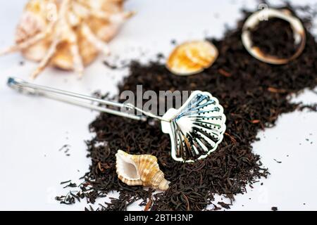 Trocknen Sie kenianische Kaimosi Teekräuter mit Muscheln und Teesieb auf weißem Hintergrund. Selektiver Fokus. Stockfoto