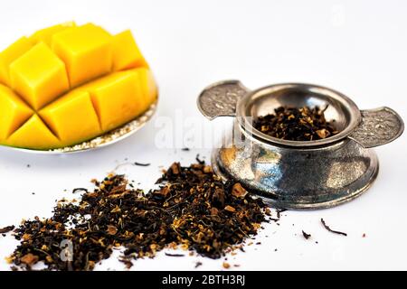 Trockene Teekräuter mit Obst und frischer Mango auf weißem Hintergrund. Selektiver Fokus. Stockfoto