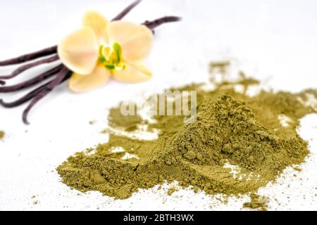 Matcha Vanille Tee Pulver mit Orchideenblüte und Vanillestäbchen auf weißem Hintergrund trocknen. Selektiver Fokus. Stockfoto