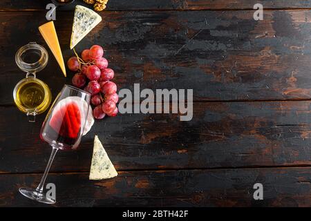 Geformte Käse und Snacks Rotwein Glas Honig Trauben auf alten vintage dunklen Holztisch Draufsicht. Freier Speicherplatz für Text Stockfoto