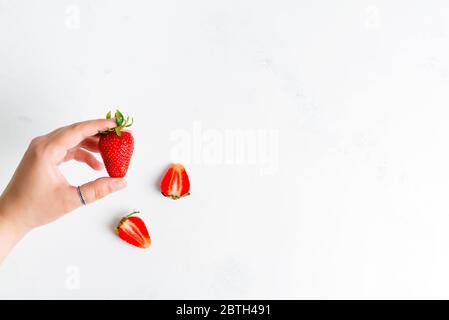 Frauenhände mit Stapel von frisch gepflückten reifen natürlichen Bio-Erdbeeren Früchte über weißem Hintergrund, kopieren Raum. Draufsicht. Veganes Food-Konzept. Stockfoto