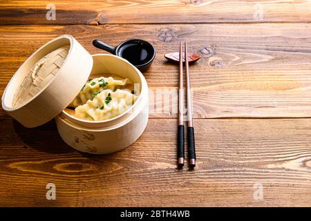 Chinesische Snacks. chinesische gedünstete Knödel. Chinesisches Konzept der traditionellen Küche. In Holzdampfer Sojasauce und Essstäbchen Seitenansicht Platz für Text. Stockfoto