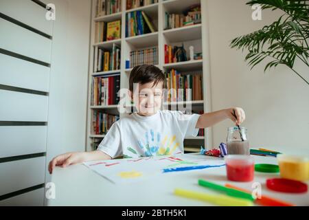 Portrait von niedlichen Jungen mit Pinsel. Kind schaut in die Kamera und lächelt mit dem Pinsel in der linken Hand. Stockfoto
