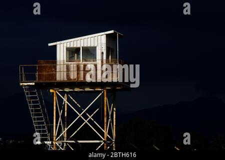 Nikosia, Zypern - 12. Februar 2020: Ein verwitterter UN-Wachturm, der von der Sonne beleuchtet wird, mit dunklen Gewitterwolken im Hintergrund. Stockfoto