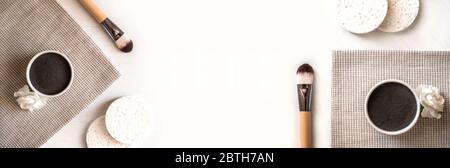 Banner aus einem Set von natürlichen kosmetischen schwarzen und blauen Gesichtsmasken in Keramikschalen auf weißem Holzhintergrund mit Pinsel. Rustikaler Stil. Stockfoto