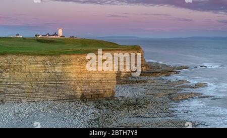 Leuchtturm Nash Point, Südwales, bei Sonnenuntergang. Der Leuchtturm liegt auf den steilen Klippen mit Blick auf den Bristol Channel Stockfoto