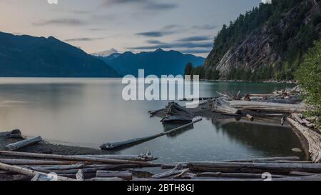 Porteau Cove am Ende eines Sommertages. Das Wasser ist ruhig und viele Holzstämme sind im Vordergrund zu sehen. Der Standort ist in BC, Kanada Stockfoto