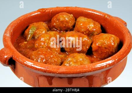 Ein kleiner Terrakotta-Topf voller Albondigas (spanische Fleischbällchen) in Tomatensauce. Stockfoto