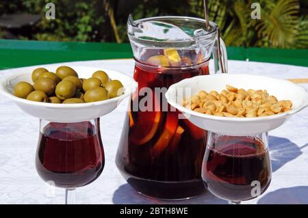 Krug und Gläser frisch zubereiteter spanischer Sangria mit Knabbereien/Tapas auf den Gläsern, um Fliegen abzuhalten, Spanien. Stockfoto