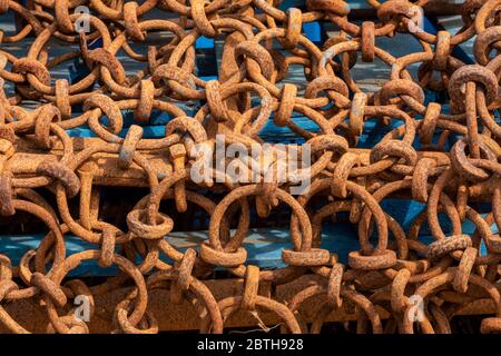 Verrostete alte Ketten schließen korrodierte Fanggeräte an einem Kai. Stockfoto