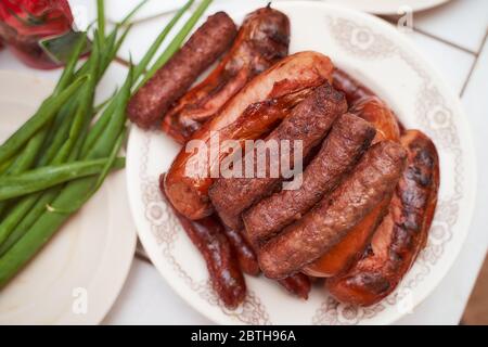 Fertigfleisch Wurst chimpchichi liegen auf einem weißen Teller in der Nähe liegt eine grüne Zwiebel Stockfoto