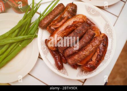 Fertigfleisch Wurst chimpchichi liegen auf einem weißen Teller in der Nähe liegt eine grüne Zwiebel Stockfoto