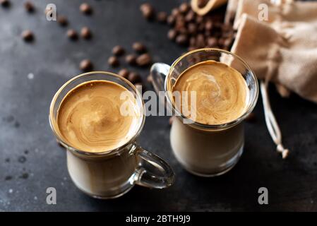 Zwei Glasbecher mit Dalgona schaumig Kaffee Trend koreanisch trinken Latte Espresso mit Kaffeeschaum auf schwarzem Hintergrund. Stockfoto