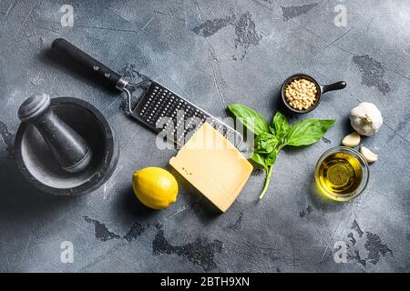 Pesto Zutaten italienisches Rezept frisches Basilikum, Tomaten Mörser Zitrone Olivenöl Parmesan Pinienkerne auf dem Steintisch auf grauem Beton Hintergrund Top vi Stockfoto