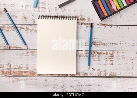 Lernen Malkonzept, Malstifte und Bleistifte auf weißem Holztisch. Leeres Skizzenbuch mit Kopierbereich. Künstlerischer Hintergrund, kreative Kunst vor Stockfoto