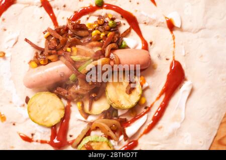 Zutaten für hausgemachte Shaverma. Wurst, Gurke, gegrilltes Gemüse liegen auf einer Pita Stockfoto