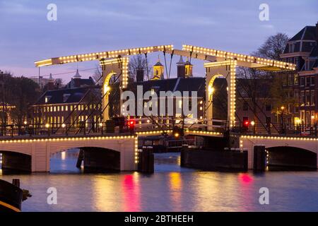 Stadtbild des Flusses Amstel mit der berühmten schmalen Brücke in Amsterdam, Niederlande, früh am Morgen im Winter Stockfoto