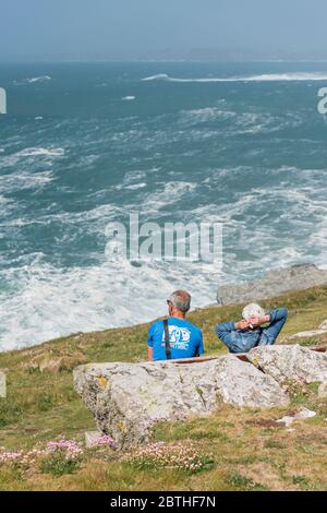 Leute sitzen und genießen den Blick über Fistral Bay an einem windigen Tag in Newquay in Cornwall. Stockfoto