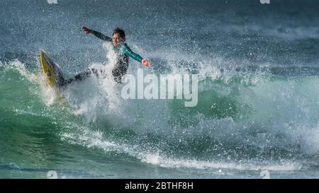 Ein Panoramabild eines Jugendlichen Surfers in dramatischer Surferaktion am Fistral in Newquay in Cornwall. Stockfoto