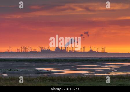 Sonnenuntergang am Wattenmeer, Blick auf Fabrikgebäude und Windkraftanlagen von Eemshaven, Niederlande Stockfoto