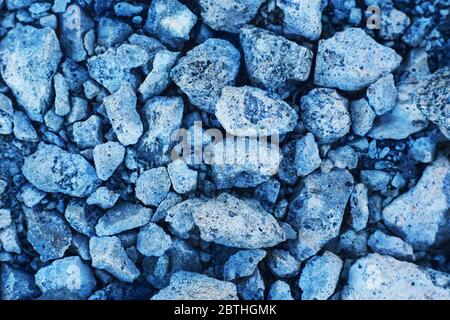 Abstrakter Hintergrund, der bläuliche Steine verschiedener Größe am Ufer eines Stausees darstellt. Stockfoto