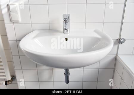 Keramik-Waschbecken mit Wasserhahn und weißen Fliesen zu Hause Stockfoto