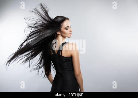 Schöne Mädchen Modell mit fliegenden Wind Haare. Eine Brünette Frau in einem schwarzen Kleid Stockfoto