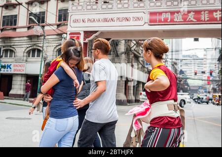 Eine Familie, die das Black Nazarene Festival im philippinischen Chinesischen Freundschaftsbogen im Chinatown Viertel Binondo auf den Philippinen besucht. Stockfoto