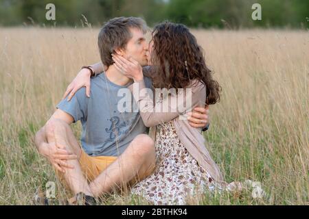 Ein junges attraktives schönes Paar lächelt zusammen in einem schönen Außenfeld zeigt ihre Liebe zueinander und küssen Stockfoto