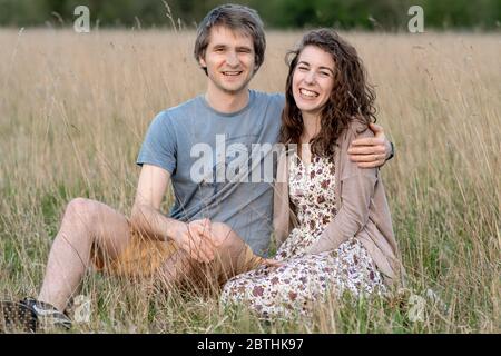 Ein junges attraktives schönes Paar lächelt zusammen in einem schönen Außenfeld zeigt ihre Liebe zueinander und küssen Stockfoto