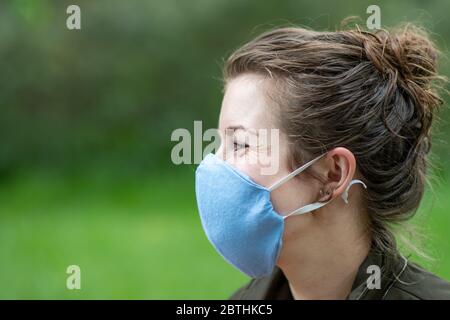Eine junge Frau trägt eine hausgemachte Gesichtsmaske Schild, um die Ausbreitung der Covid Coronavirus Pandemie zu verhindern Stockfoto