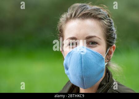 Eine junge Frau trägt eine hausgemachte Gesichtsmaske Schild, um die Ausbreitung der Covid Coronavirus Pandemie zu verhindern Stockfoto