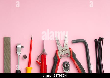 Hauswartung, Service, diy-Konzept. Werkzeuge für Holz, Metall und andere Bauarbeiten. Draufsicht auf DIY-Werkzeuge. Home Reparaturen. Auf rosa Hintergrund. Stockfoto