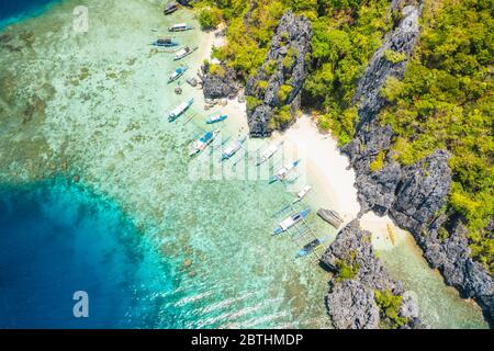 Luftaufnahme der Tagesausflüge Boote, die auf der tropischen Shimizu Insel festgemacht sind. Kalkstein Küstenfelsen, weißer Sandstrand in blauem Wasser. El Nido, Palawan Stockfoto