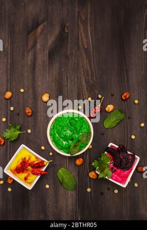 Hummus, gesunde vegane (vegetarische) Speisen. Verschiedene drei Typen: Classic, Minze und Rote Bete. Edamame trockene Bohnen, Gewürze, frische Blätter. Trendy schwarz Woode Stockfoto