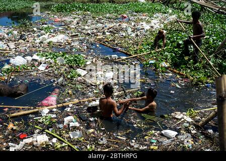 Makassar, Indonesien. Mai 2020. Ein Junge schwimmt im Müll in den Slums, Makassar City, Süd-Sulawesi, Indonesien, 26. Mai 2020. Mit der weltweiten Pandemie steigt die Menge an Plastikmüll an und es besteht ein hohes Risiko, weggeworfene medizinische Geräte, die bei Coronavirus-Patienten verwendet werden, zu übertragen. (Foto: Ali Fahmi/INA Photo Agency/Sipa USA) Quelle: SIPA USA/Alamy Live News Stockfoto