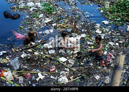 Makassar, Indonesien. Mai 2020. Ein Junge schwimmt im Müll in den Slums, Makassar City, Süd-Sulawesi, Indonesien, 26. Mai 2020. Mit der weltweiten Pandemie steigt die Menge an Plastikmüll an und es besteht ein hohes Risiko, weggeworfene medizinische Geräte, die bei Coronavirus-Patienten verwendet werden, zu übertragen. (Foto: Ali Fahmi/INA Photo Agency/Sipa USA) Quelle: SIPA USA/Alamy Live News Stockfoto