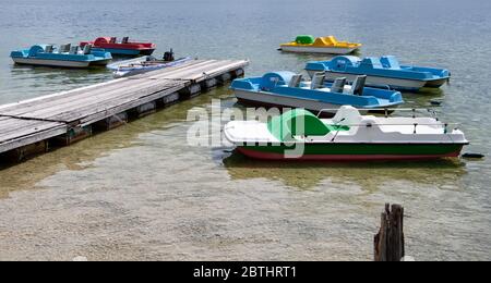 Utting, Deutschland. Mai 2020. Bunte Tretboote liegen an einem Steg am Ammersee. Kredit: Sven Hoppe/dpa/Alamy Live News Stockfoto