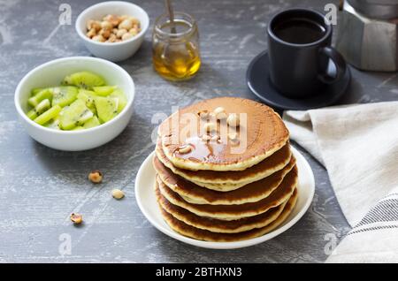 Vegetarisches Frühstück mit Pfannkuchen, Kaffee, Honig, Nüssen und Obst. Stockfoto