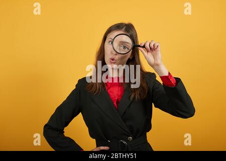 Fokussierte Frau hält EIN Vergrößerungsglas in der Hand und schaut durch das Auge Stockfoto