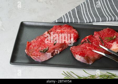 Zwei frische rohe Fleischsteaks auf schwarzer Keramikplatte Stockfoto