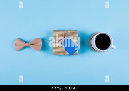 Tasse Kaffee, Geschenk und Fliege auf blauem Hintergrund. Draufsicht im Flat Lay-Stil. Happy Fathers Day Konzept. Stockfoto