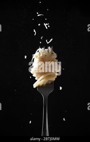 Gabel mit Spaghetti bestreut Käse und Pfeffer auf dunklem Hintergrund. Cacio e Pepe – Italienische Pasta. Stockfoto