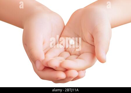 Nahaufnahme der Hand eines kleinen Jungen, der den ersten gefallenen Milchzahn in seinen gekreuzten Handflächen auf weißem Hintergrund isoliert hält Stockfoto