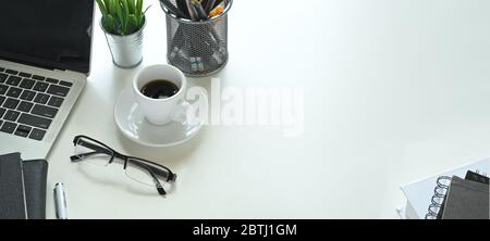 Foto von Keramik Kaffeetasse mit kleinen Schüssel setzen auf weißen Schreibtisch, die von schwarzen leeren Bildschirm Computer Laptop, Topfpflanze, Stift, pe umgeben Stockfoto