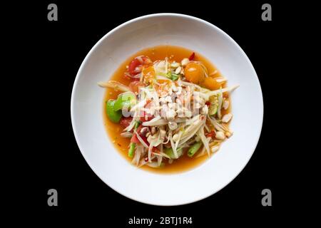 Grüner Papaya-Salat in weißer Schüssel auf schwarzem Hintergrund isoliert. Thai-Essen lecker und beliebt Stockfoto