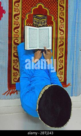Muslimischer Junge las den heiligen Koran, als er Namas auf Jumat-UL-Wida in seinem Haus vor dem Eid al-Fitr Festival in Beawar anbot. Stockfoto