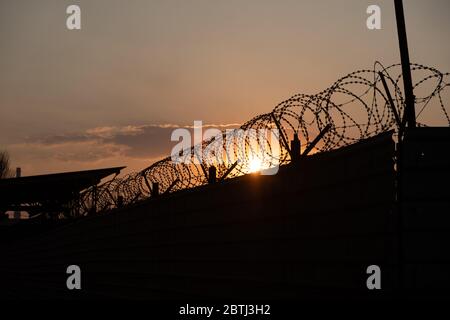 Silhouette von Stacheldraht Zaun mit Dämmerung Himmel. Stacheldraht von eingeschränkt Stockfoto